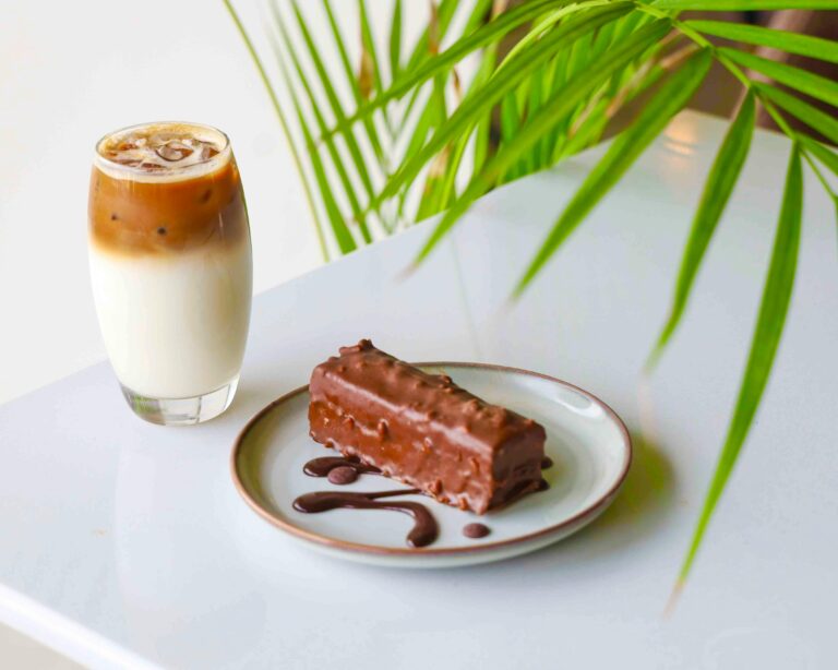 A refreshing iced coffee paired with a chocolate dessert on a white table in a modern setting.