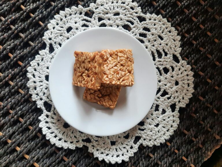 Tempeh on a white plate atop a crochet doily offers a cozy and appetizing presentation.